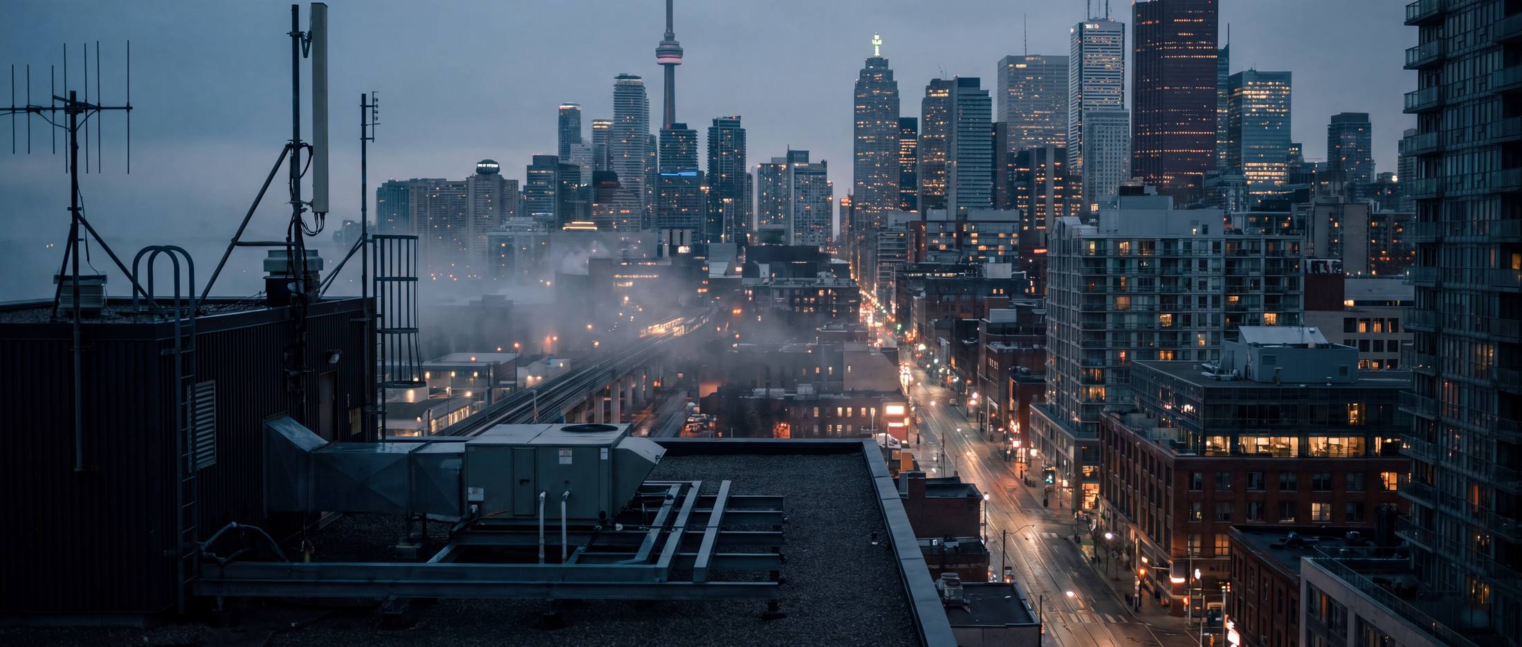 The Toronto skyline at dusk from a rooftop, streets glowing below