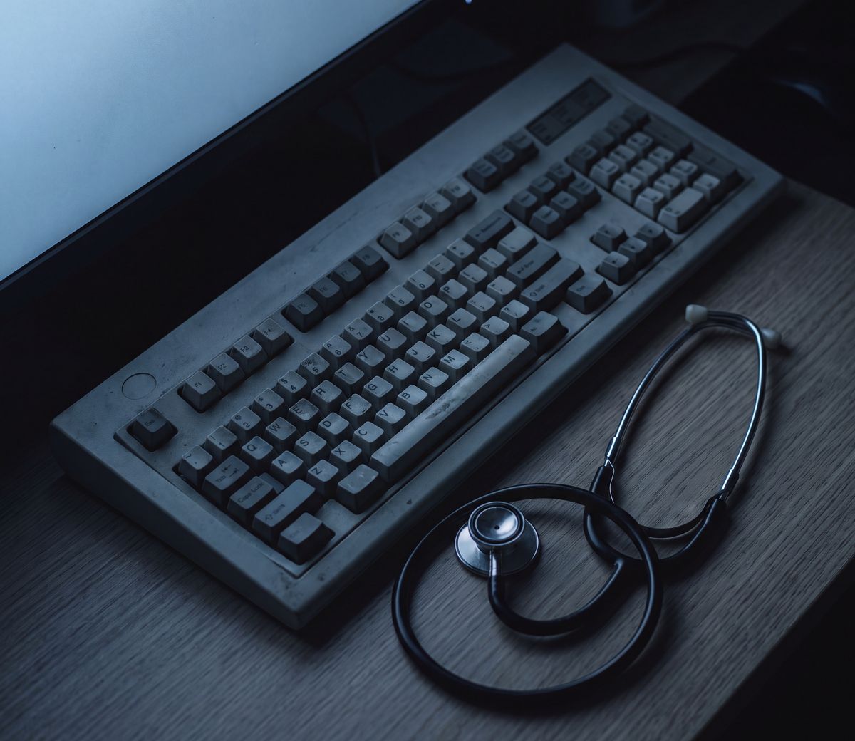 A keyboard and a stethoscope resting side by side on a desk