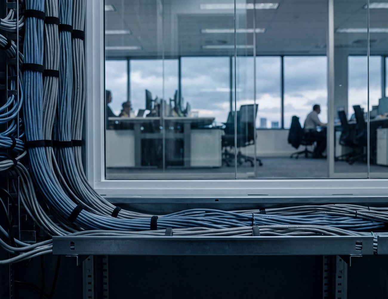 Structured network cabling running along a rack, an office visible through the window